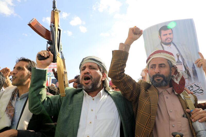 Houthis brandish their weapons and hold up portraits of leader Abdul Malik Al Houthi during a protest in Yemen on January 12. AFP