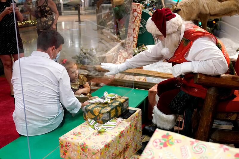 Federica Rodriguez is greeted by Santa Claus from behind a transparent barrier in Miami. AP Photo