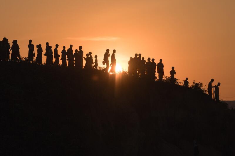 TOPSHOT - Rohingya Muslim refugees  walk down a hillside in the  Kutupalong refugee camp in Cox's Bazar on November 26, 2017.
Rohingya refugees who return to Myanmar from Bangladesh following a repatriation agreement will initially live in temporary shelters or camps, Dhaka said November 25, a day after the UN raised concern for their safety when they go back. The United Nations says more than 620,000 Rohingya have fled to Bangladesh since August and now live in squalor in the world's largest refugee camp after a military crackdown in Myanmar that the UN and Washington have said clearly constitutes "ethnic cleansing". / AFP PHOTO / Ed JONES