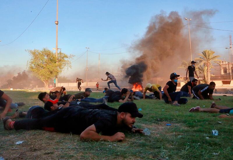 Anti-government protesters take cover while Iraq security forces fire during a demonstration in Baghdad, Iraq.   AP