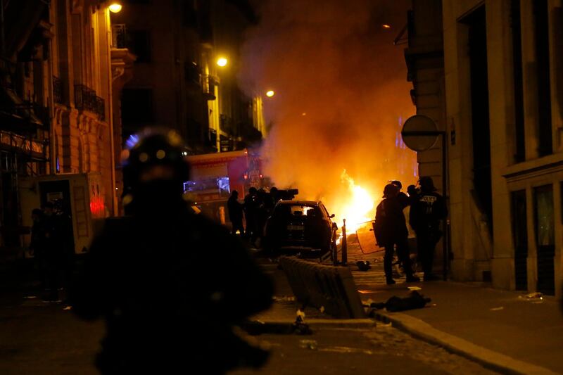 French police officers watch a car burning near the Champs-Elysee. AP