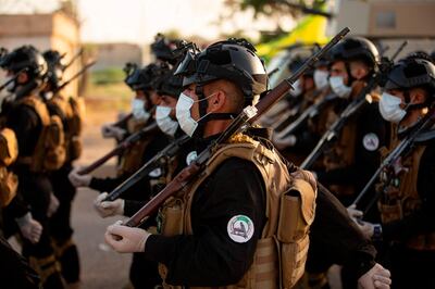 (FILES) In this file photo taken on June 14, 2020 Mask-clad members of the Hashed al-Shaabi (Popular Mobilisation) paramilitary force take part in a military parade in the southern Iraqi city of Basra, marking the sixth anniversary of its founding after Iraq's top Shiite cleric Grand Ayatollah Ali Sistani called to defend the country from the Islamic State group (IS). Around the corner from Iraq's holiest shrines, a years-long struggle over resources and reputations is coming to a head -- threatening a dangerous schism within a powerful state-sponsored security force. The growing fissure pits the vast Iran-aligned wing of the Hashed al-Shaabi network against four factions linked to the shrines of Iraq's twin holy cities, Karbala and Najaf. / AFP / Hussein FALEH
