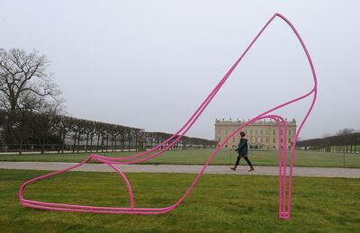 A woman walks past a giant shoe sculpture by Irish artist Michael Craig-Martin in the grounds of the ancestral seat of the Dukes of Devonshire, Chatsworth House, near Bakewell in Derbyshire, northern England on March 12, 2014. The work is part of a three-part exhbition by the artist that includes twelve large scale sculptures placed in the historic gardens and landscape of Chatsworth and vibrantly coloured plinths inside.   AFP PHOTO / ANDREW YATES  --   RESTRICTED TO EDITORIAL USE, MANDATORY MENTION OF THE ARTIST UPON PUBLICATION, TO ILLUSTRATE THE EVENT AS SPECIFIED IN THE CAPTION (Photo by ANDREW YATES / AFP)