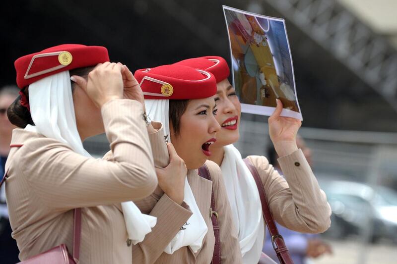 Airline stewards watch the Emirates Airbus A380, the world's largest passenger airliner, land at Begumpet Airport for the India Aviation 2014 airshow. Noah Seelam