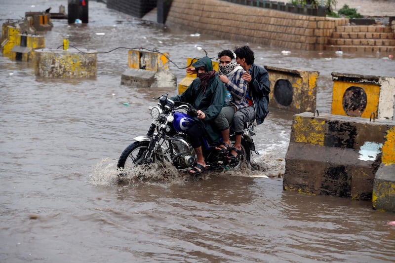 Yemenis ride a motorcycle through a flooded street following heavy rains in the old quarter of Sana'a, Yemen.  EPA