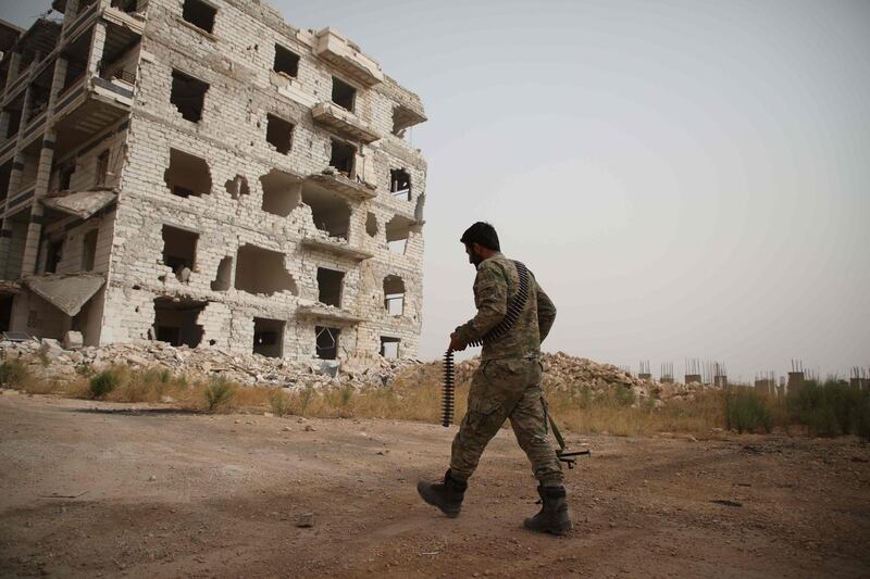 A Syrian rebel-fighter from the National Liberation Front (NLF) walks in a street in the rebel-held Al Rashidin district of western Aleppo's countryside near Idlib province. AFP