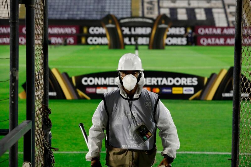 An employee in protective suit is seen before a closed-door Copa Libertadores group phase football match between Peru's Alianza Lima and Argentina's Racing at the Alejandro Villanueva Stadium in Lima. AFP