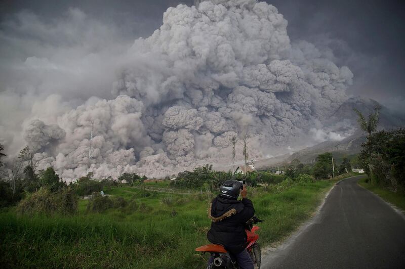 An Indonesian man takes a picture of the Mount Sinabung volcano as it spews thick volcanic ash into the air in Karo, North Sumatra. Endro Rusharyanto / AFP