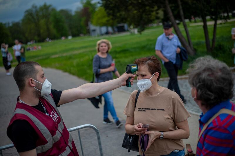 A security member measures the temperature of visitor as people attend a concert of Chinaski music band in Prague, Czech Republic. EPA