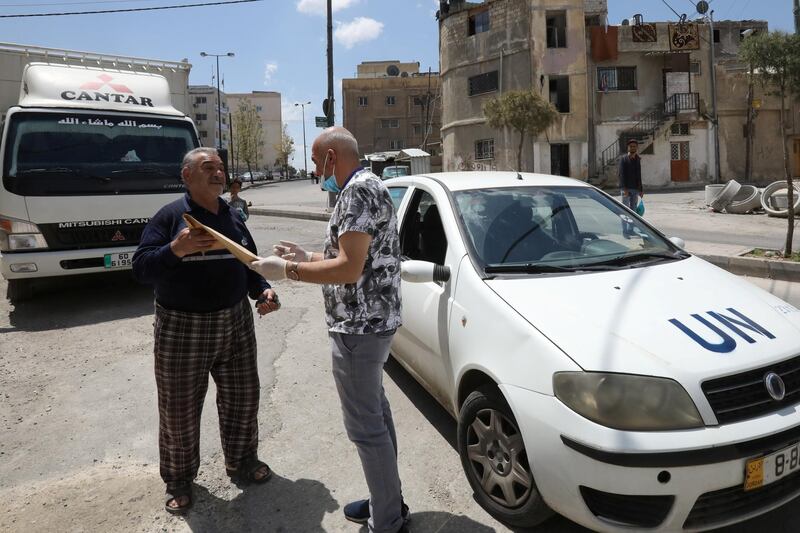 A refugee receives his prescription medicine from a member of the medical staff at UNRWA in front of his home at Amman New camp. REUTERS