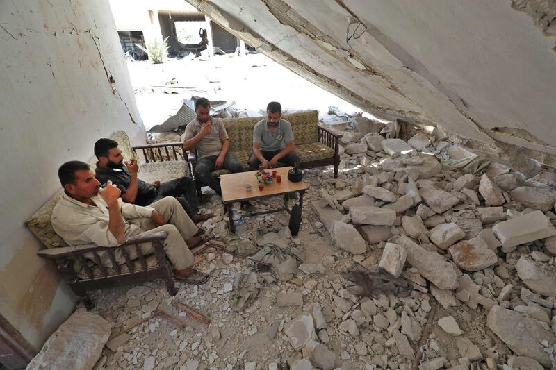Abu Abdullah (2nd-L), a Syrian displaced from the town of Khan Sheikhun in the south of the northwestern Idlib province, sits for tea with his former neighbours at his now-destroyed home upon returning during a temporary truce, in Khan Sheikhun on August 3, 2019. Damascus resumed air strikes on northwest Syria's Idlib on August 5, a war monitor said, scrapping a ceasefire for the jihadist-run bastion and accusing its opponents of targeting an airbase of its ally Russia. / AFP / Omar HAJ KADOUR
