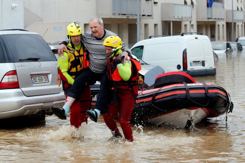 Rescue workers move a man out of a flooded street.