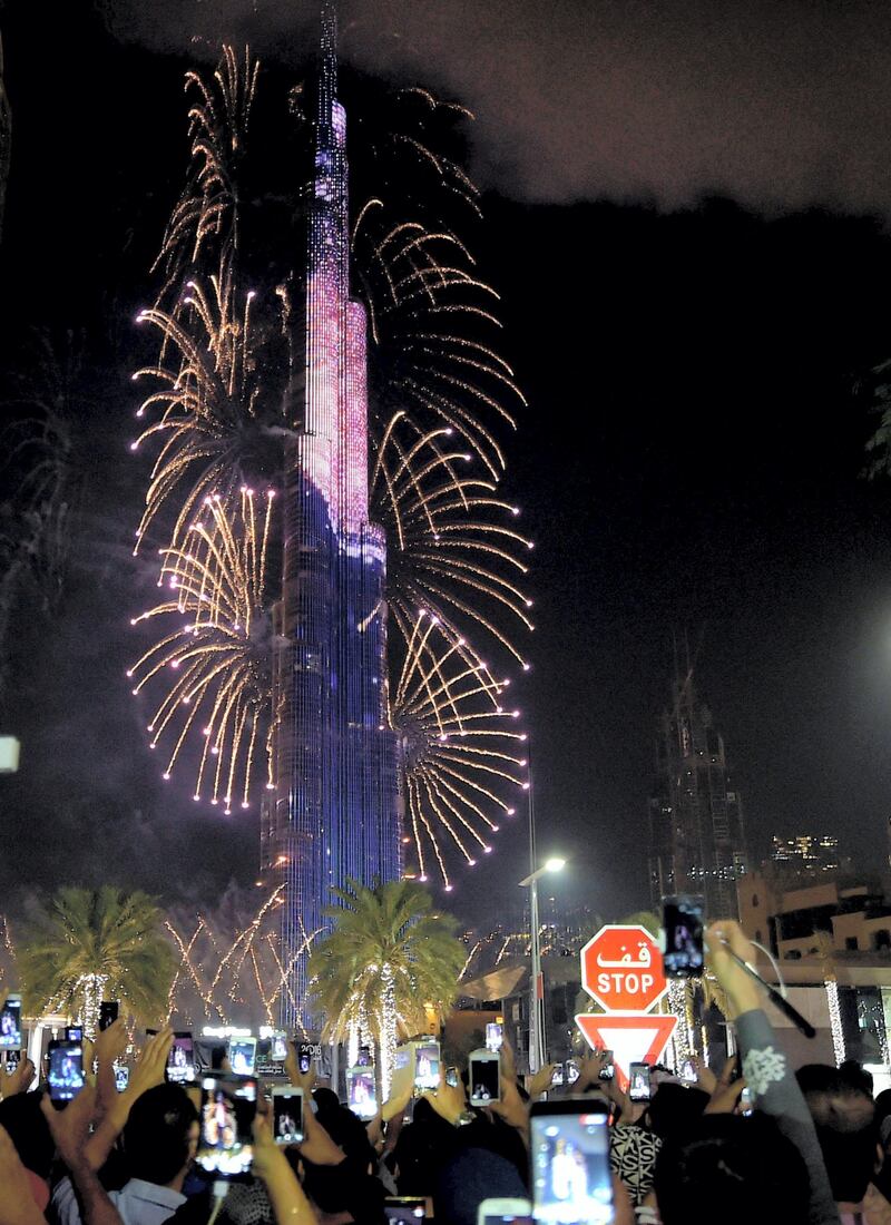 Smoke billows from the Address Downtown Hotel, after it caught on fire hours earlier, past fireworks, near the Burj Khalifa, the world's tallest tower in Dubai, on January 1, 2016. At least 16 people were injured when a huge fire ripped through a luxury 63-storey hotel, the Address Downtown, where crowds were gathering to watch New Year's Eve celebrations. The cause of the blaze was not immediately known but the building was safely evacuated. AFP PHOTO / AHMAD FARWAN (Photo by AHMAD FARWAN / AFP)