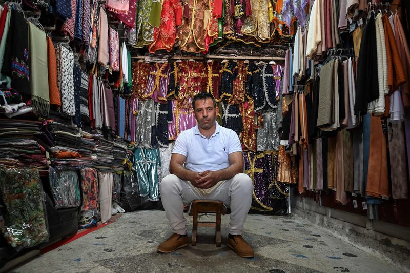 Syrian refugee Ahmad Ibrahim, 31, poses inside his textile shop in Sanliurfa, Turkey. Inflation has surged and the value of the Turkish lira has dropped.