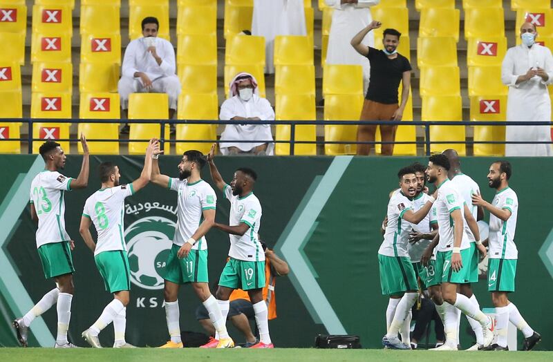 Yasser Al-Shahrani celebrates with teammates after scoring Saudi Arabia's first goal against Palestine as fans cheer from the stands. Reuters