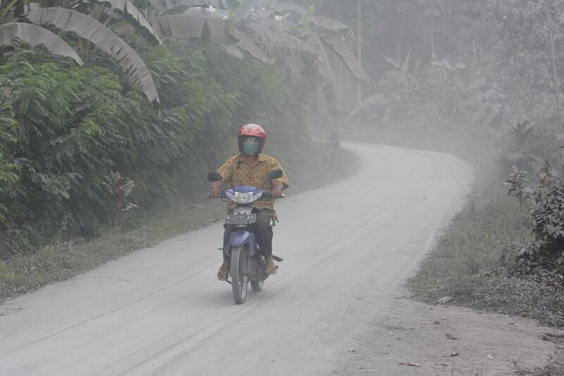 A motorist rides on a road covered in volcanic ash from the eruption of Mount Semeru. AP