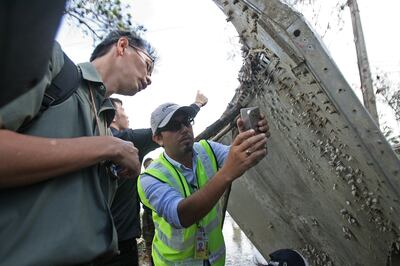 A Malaysian official, centre, takes pictures of a piece of suspected aircraft debris after it was found by fishermen on January 23, 2016. AFP