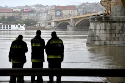 Firemen stand at Margit Bridge, where the wreck of a sightseeing boat was found on the Danube River in downtown Budapest, Hungary, Thursday, May 30, 2019, after a sightseeing boat sank. A massive search was underway on the river for 21 people missing after the sightseeing boat with 33 South Korean tourists sank after colliding with another vessel during an evening downpour. (Zoltan Mathe/MTI via AP)