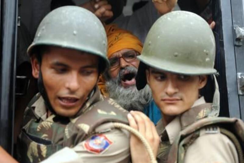 Indian security personnel stand in front of an arrested supporter of Indian social activist Anna Hazare (C) as he shouts slogans from a police bus in New Delhi on August 16, 2011. Indian police have detained a 73-year old anti-corruption campaigner, Anna Hazare, as he prepared to push ahead with a banned hunger strike in New Delhi, witnesses said. The police action came in front of hundreds of Hazare supporters who had gathered to back his "fast unto death" aimed at pressuring the government into strengthening a new anti-corruption law. AFP PHOTO/RAVEENDRAN
 *** Local Caption ***  620253-01-08.jpg