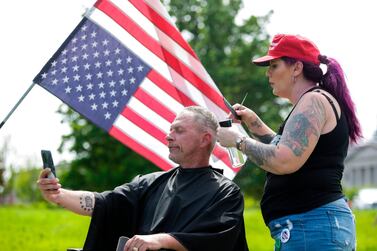 Trump supporter Laina Moore of Elma, Washington gives a haircut to Darren Culbertson of Yelm, Washington on the lawn of the State Capitol as people protest a stay-at-home order which prohibits barbers and stylists from taking clients, Olympia, Washington, May 9. About 1,500 people rallied against Governor Jay Inslee’s stay-at-home order. Jason Redmond / AFP