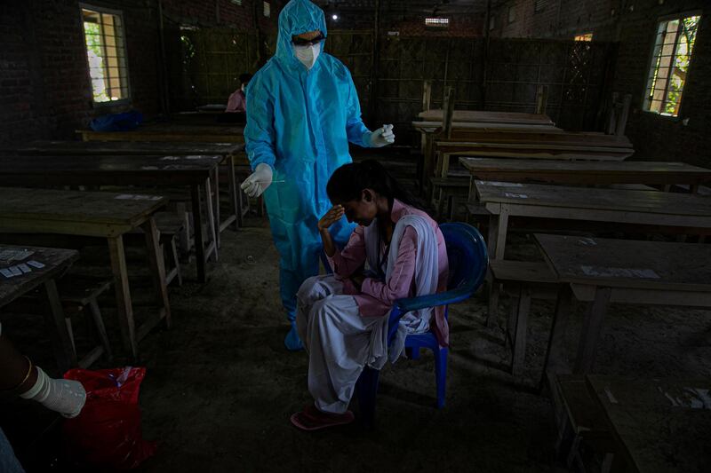 A reluctant student gestures hesitantly before a health worker takes her nasal swab sample after classes started at a college in Jhargaon village, outskirts of Gauhati, India. AP Photo