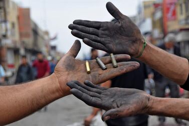 Men holding up spent bullet casings found at a protest site in Habboubi Square in Iraq's southern city of Nasiriyah in Dhi Qar province. AFP