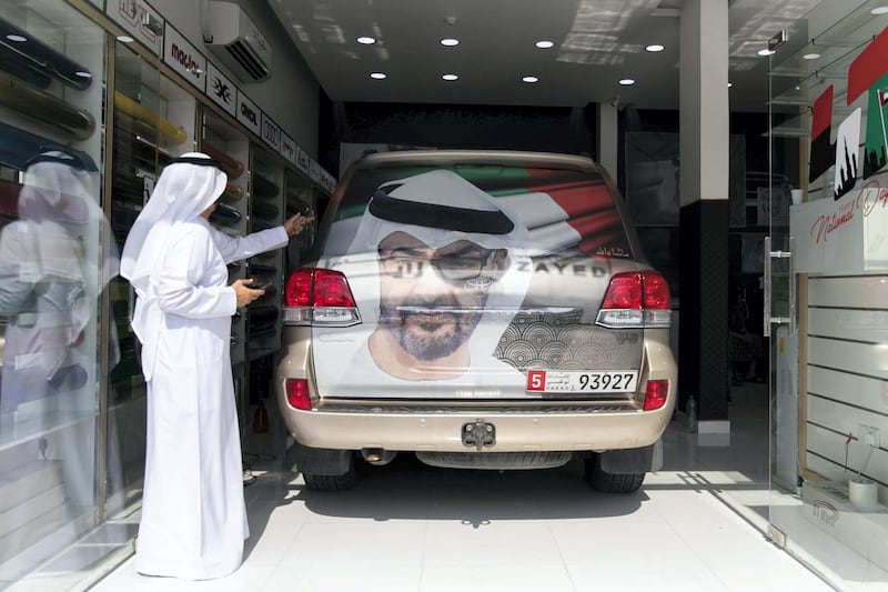 ABU DHABI, UNITED ARAB EMIRATES - NOVEMBER 27, 2018. 

Rashid Al Muhairbi, who's birthday falls on UAE National's day, decorates his car at Grand Plus Auto Accessories. 

Car accessory shops in Mussafah are keeping busy as motorists rush to dress up their vehicles ahead of the UAE's 47th National Day.

(Photo by Reem Mohammed/The National)

Reporter:  HANEEN DAJANI
Section:  NA