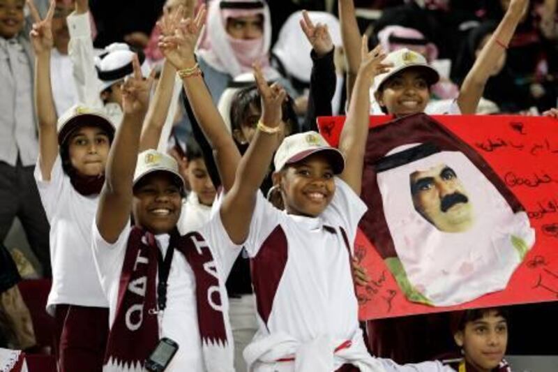 Young Qatari soccer supporters gesture, as they display a poster of Qatar's Emir Sheik Hamad bin Khalifa al-Thani, prior to the opening ceremony of the AFC Asian Cup Soccer at Khalifa Stadium, in Doha, Qatar, Friday Jan. 7, 2011. (AP Photo/Hussein Malla) *** Local Caption ***  XHM104_Qatar_Asian_Cup_Soccer.jpg