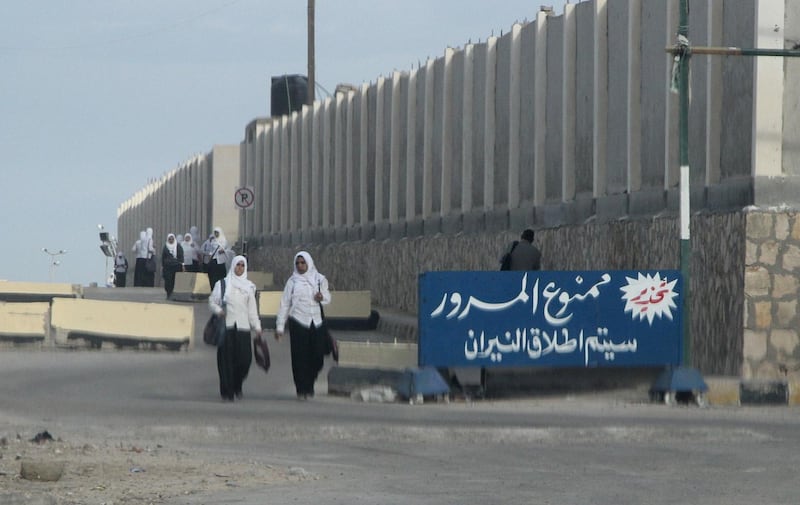 Egyptian schoolgirls pass by a sign in Arabic reading "no passing, will open the fire’’  al-Arish in the Sinai peninsula on November 17, 2014. With soldiers firing warning shots to herald the nightly curfew and jihadist militants beheading informants, Sinai's residents find themselves caught in the middle of Egypt's "war on terror".  AFP PHOTO / STR / AFP PHOTO / STR