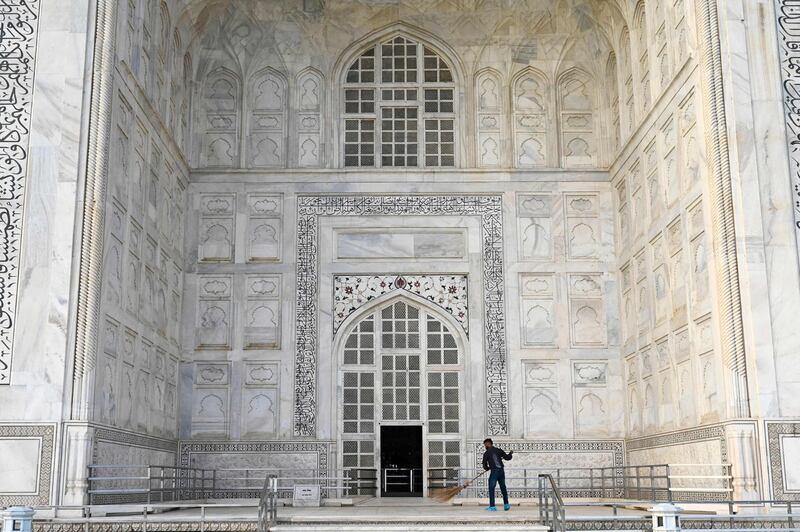 A worker sweeps in front of an entrance of the Taj Mahal ahead of the reopening. AFP