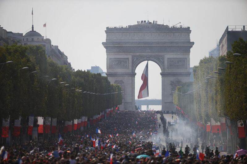 Supporters gather on the Champs-Elysees avenue near the Arch of Triumph (Arc de Triomphe) in Paris on July 16, 2018 as they wait for the arrival of the French national football team for celebrations after France won the Russia 2018 World Cup final football match on the previous night. / AFP / CHARLY TRIBALLEAU
