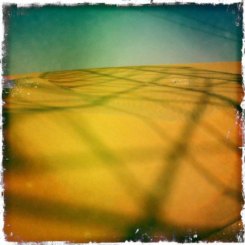 Day trip with friends to the Western Region and the Mazayin Dhafra Camel Festival, 220 kms west of Abu Dhabi on December 20, 2013. High tension wires cast a shadow over sand dunes.  Picture taken with the Hipstamatic app for the iPhone. Liz Claus / The National