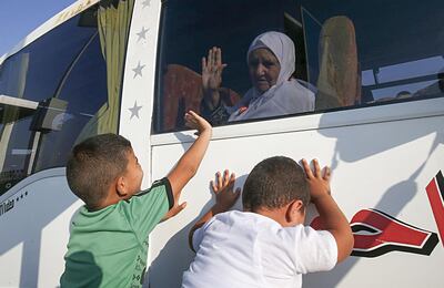 A Palestinian Muslim pilgrim waves to her relatives as she sits in a bus at the Rafah border crossing between the Gaza Strip and Egypt on July 25, 2019, as pilgrims wait to cross into Egypt on their way to Saudi Arabia for the annual Hajj pilgrimage. The Hajj, largest annual pilgrimage in the world, is the fifth pillar of Islam, a religious duty that must be carried out at least once in the lifetime of every able-bodied Muslim who can afford to do so. / AFP / SAID KHATIB
