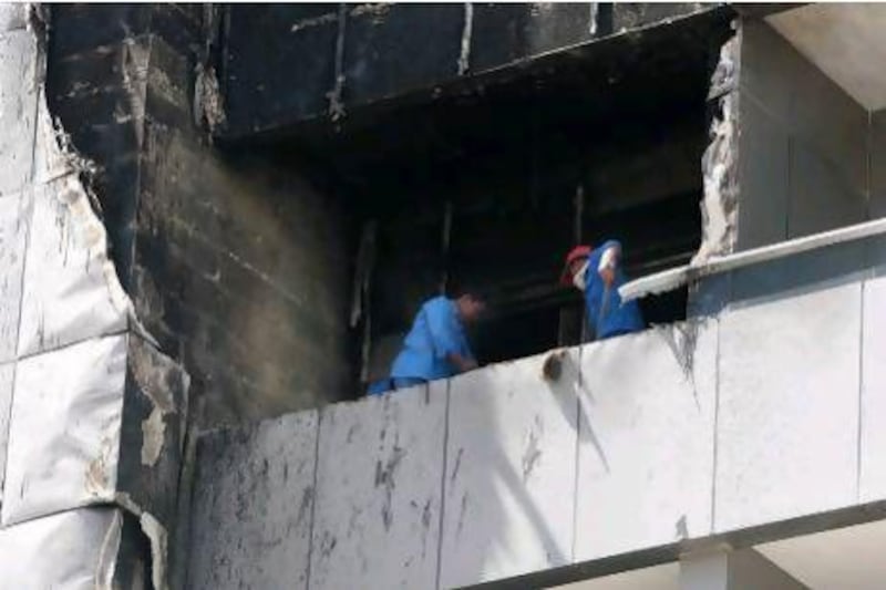 Workers cleaning the balcony of one of the damaged flat in Saif Belhasa building in Tecom area in Dubai.