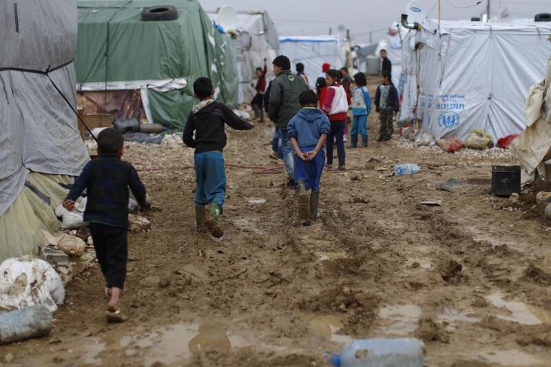 Syrian refugee children walk in mud at a refugee camp in the town of Hosh Hareem. (Hassan Ammar / AP)