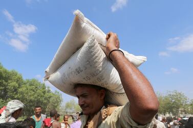 A man carries sacks of grain he received from an ICRC aid distribution centre in Bajil, Yemen. Reuters. File.