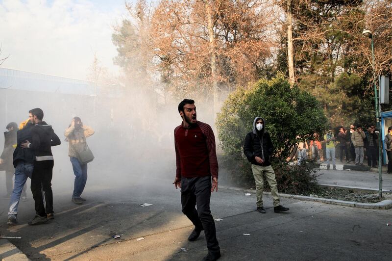 In this photo taken by an individual not employed by the Associated Press and obtained by the AP outside Iran, university students attend a protest inside Tehran University while a smoke grenade is thrown by anti-riot Iranian police, in Tehran, Iran, Saturday, Dec. 30, 2017. A wave of spontaneous protests over Iran's weak economy swept into Tehran on Saturday, with college students and others chanting against the government just hours after hard-liners held their own rally in support of the Islamic Republic's clerical establishment. (AP Photo)