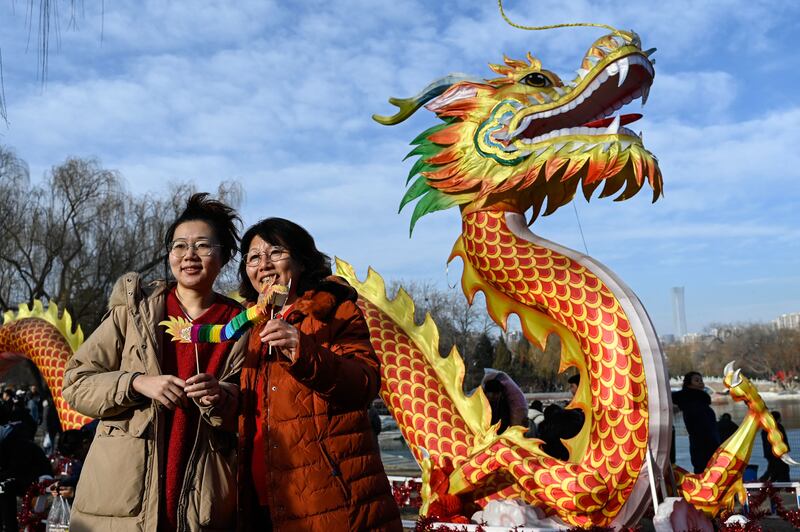 Women pose for a photograph next to a dragon figure at the Longtan Park Fair on the second day of the Lunar New Year of the Dragon in Beijing. AFP