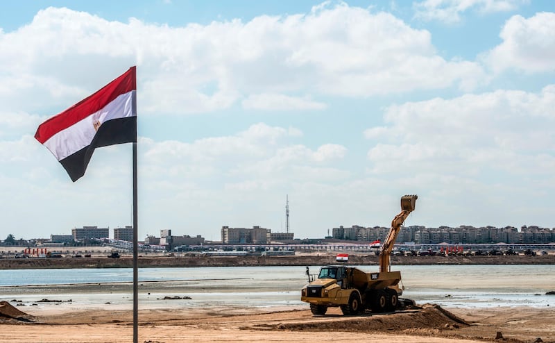 A picture taken on October 21, 2017, shows an Egyptian flag flying near a construction digger at the site of the New Alamein City, situated about 100 kilometres (62 miles) west of the northern city of Alexandria. / AFP PHOTO / KHALED DESOUKI