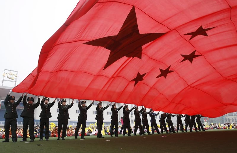 People's Liberation Army soldiers wave a Chinese national flag at a stadium in Beijing. Kevin Zhao / Reuters