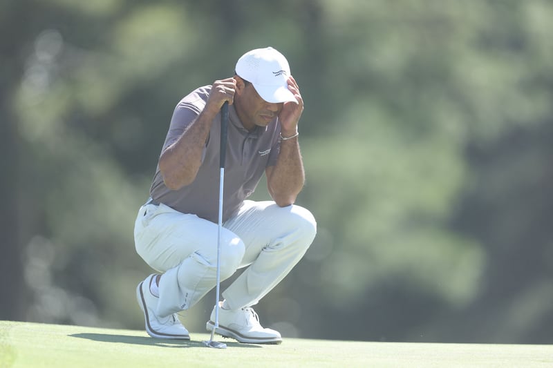 Tiger Woods shields his face from sand on the 18th green at Augusta. AFP