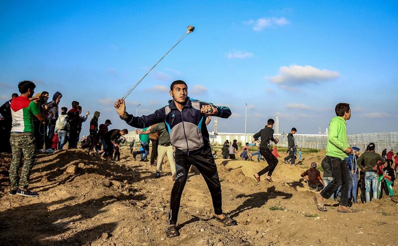 TOPSHOT - A Palestinian protester uses a slingshot to hurl objects during clashes with Israeli forces across the fence following a demonstration by the border with Israel east of Gaza City on March 22, 2019.  / AFP / Said KHATIB
