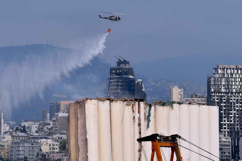 Water is dropped from a military helicopter to tackle the fire at the silos. EPA