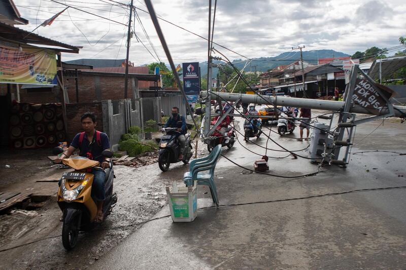 People ride their motorbikes past a collapsed electric pole in the aftermath of an earthquake in Mamuju, West Sulawesi, Indonesia, 16 January 2021. At least 42 people died and hundreds were injured after a 6.2 magnitude earthquake struck Sulawesi island on 15 January.  EPA
