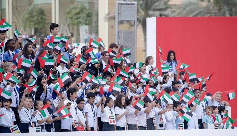 Children hold UAE flags in Burj Khalifa area. Wam