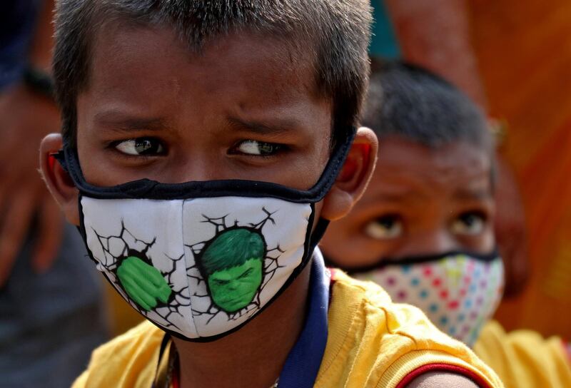 Children wearing protective masks wait to enter the Lokmanya Tilak Terminus railway station in Mumbai, India. Reuters