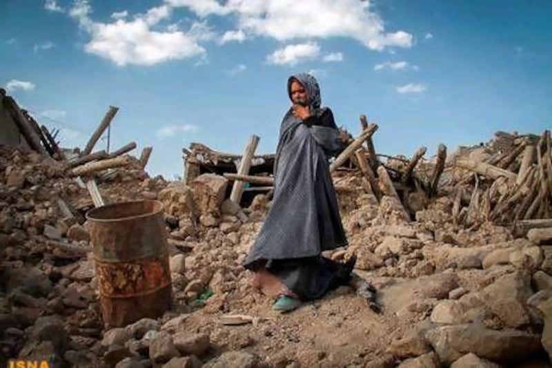 An earthquake victim stands near damaged houses in an earthquake-stricken town in Iran.
