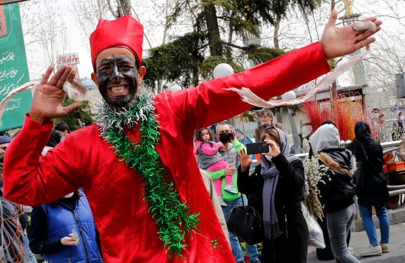An Iranian man dressed as Haji Firuz, the traditional herald of Nowruz, the Persian New Year, dances and collects money among the people shopping at a street market for the festivities, in Tehran. Traditionally, Iranians buy goldfish and flowers to mark Nowruz, which this year falls on March 20. EPA