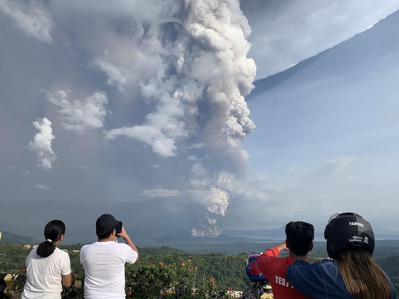 People take photos of a phreatic explosion from the Taal volcano as seen from the town of Tagaytay in Cavite province. AFP