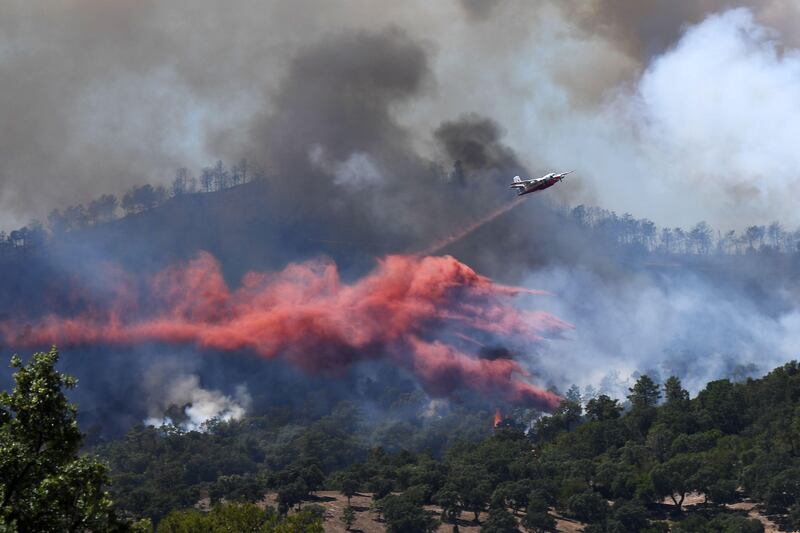 A fire fighting Canadair aircraft drops fire retardant over a fire near Bormes-les-Mimosas, southeastern France, on July 26, 2017. At least 10,000 people, including thousands of holidaymakers, were evacuated overnight after a new wildfire broke out in southern France, which was already battling massive blazes, authorities said on July 26. Anne-Christine Poujoulat/AFP Photo